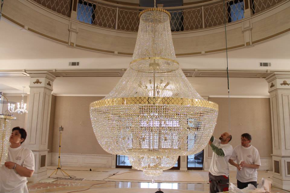 Heavy crystal chandelier installation in London hallway